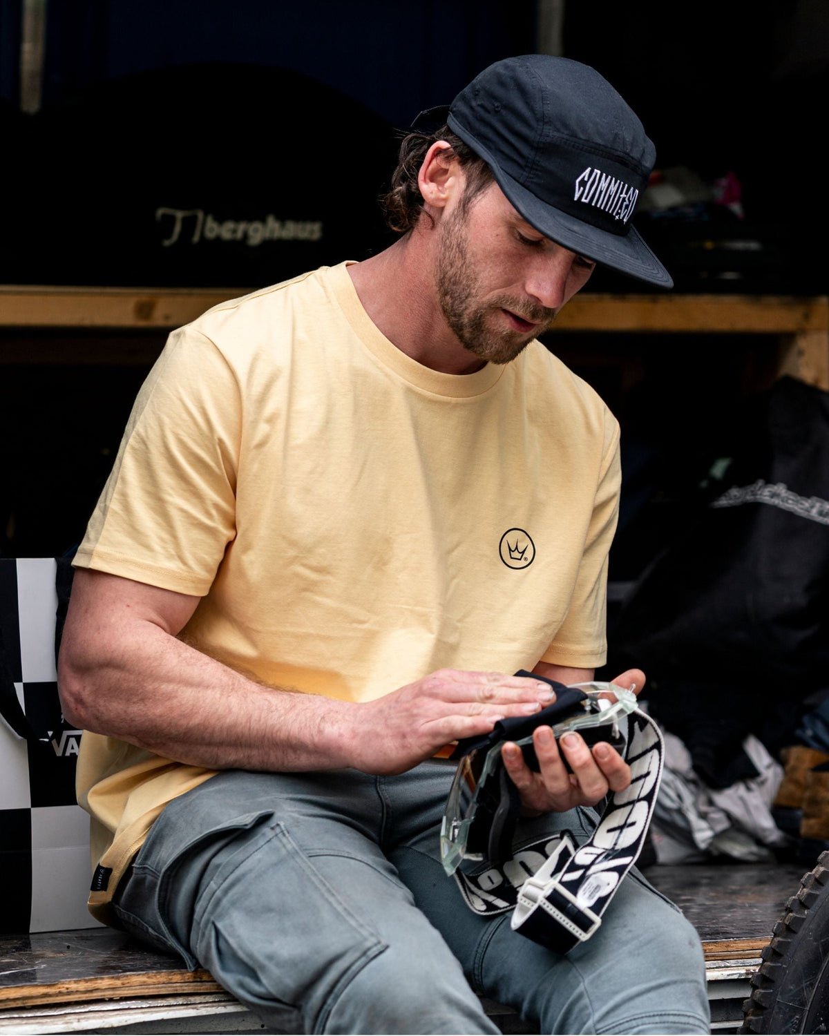 Model sitting outdoors wearing Peaty's Playground T-shirt in Vintage Yellow
