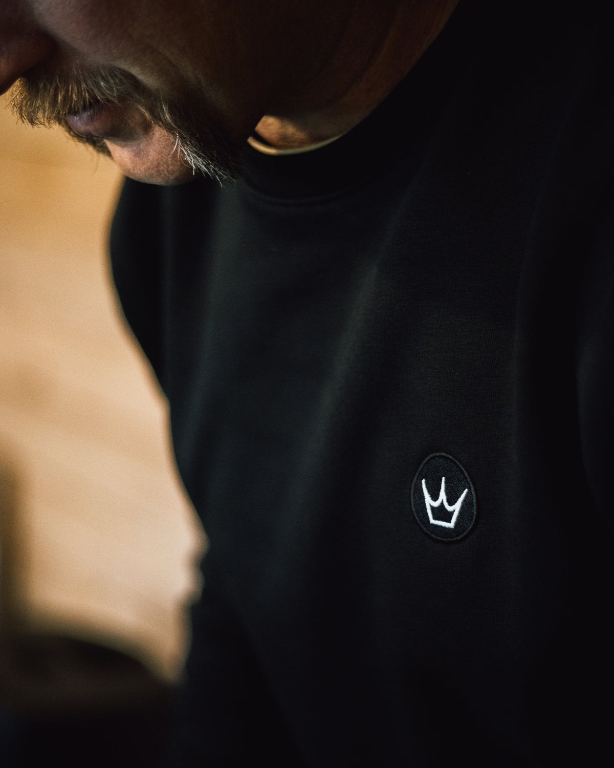 Close-up of the Peaty's embroidered crown emblem on a Black Crown Crew sweatshirt