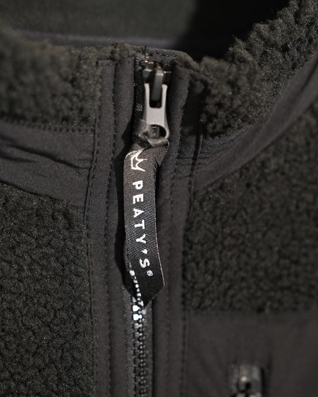 Black Wharncliffe Fleece close-up of Peaty's branded zip pull and sherpa fabric