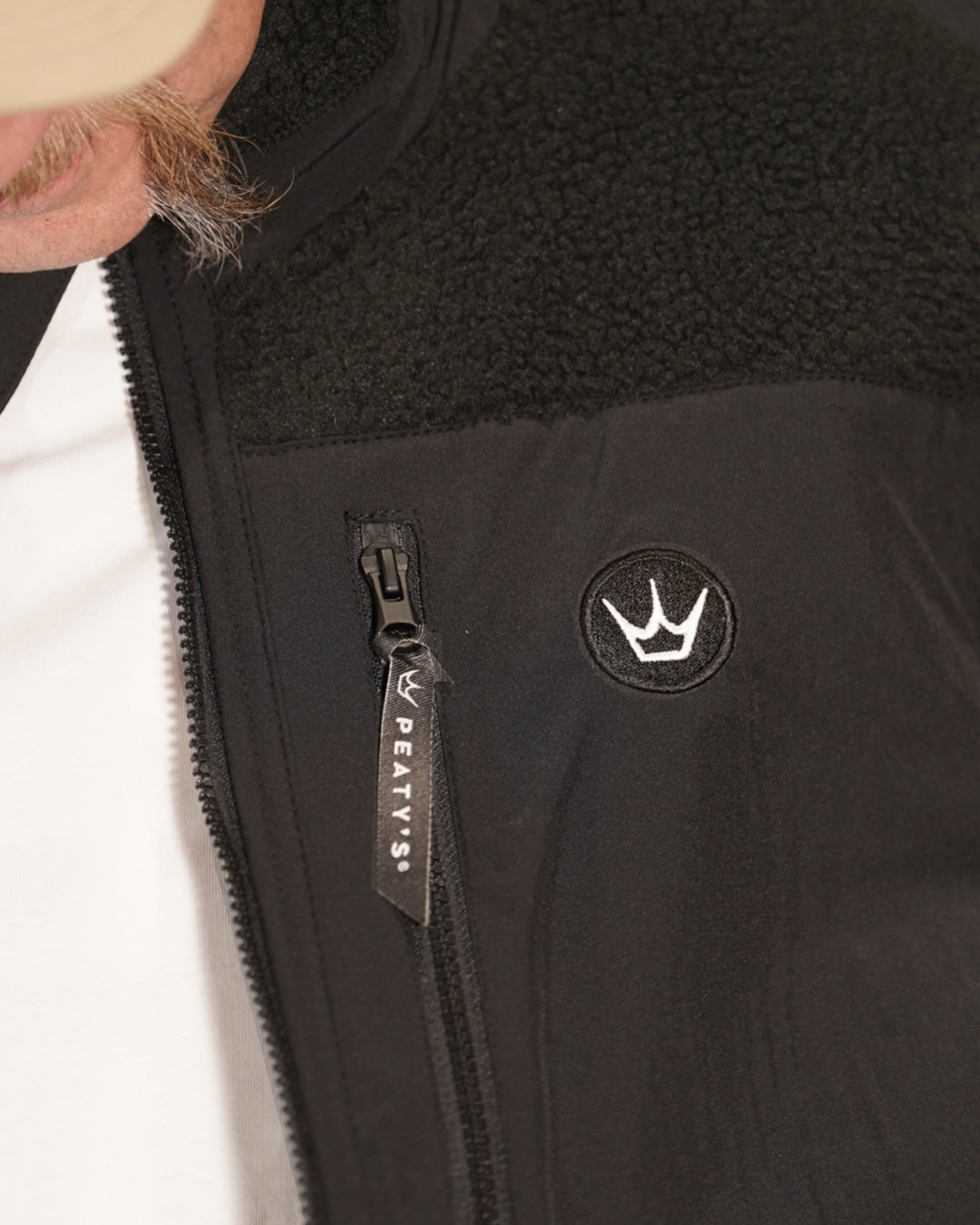 Black Wharncliffe Fleece chest detail showing Peaty's crown badge and branded pocket zip