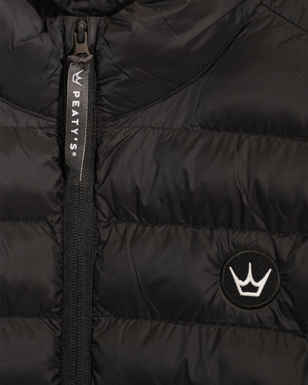 Black Grenoside Gilet close-up showing quilted recycled nylon, Peaty's crown chest branding and front zip