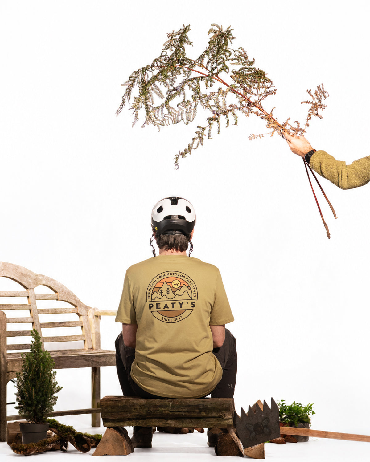 Rider wearing a Faded Olive Peaty's Playground T-shirt while seated outdoors, showing the back design